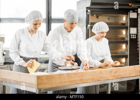 Drei Bäcker Spaß bilden Teig zum backen zusammen, der auf die moderne Fertigung Stockfoto