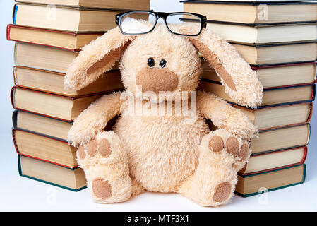 Ein Spielzeug, das Kaninchen in Brille sitzt in der Nähe von Stapel der Bücher. Stockfoto