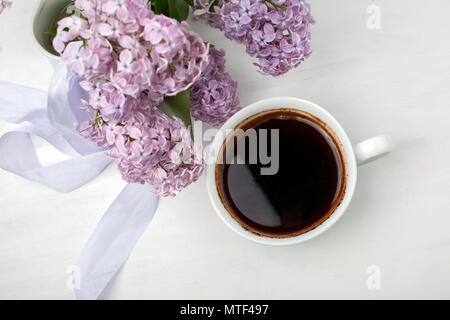 Blumige Komposition aus schönen lila lila auf weiß Holz- Hintergrund mit Tasse Kaffee. Stockfoto