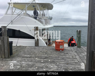 Zwei Coast Guard Station Shinnecock Crewmitglieder Verhalten einen Beitrag Suche und Rettung Verpflegung an Bord der Kristen Lynn, ein 54-Fuß-sportboote Samstag, 22. April 2017, an der Oakland Marina, in Hampton Buchten, New York. Eine Station Shinnecock boatcrew unterstützt die Kristen Lynn nach benachrichtigt wird, dass die Kristen Lynn auf das Wasser in der Nähe von Shinnecock Einlass. Stockfoto