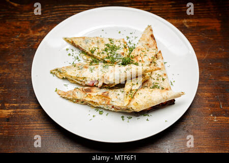 Auf eine Platte von pita Brot mit Käse, bestreut mit Kräutern. Die Platte steht auf einem Holz- Oberfläche. Horizontale Foto Stockfoto