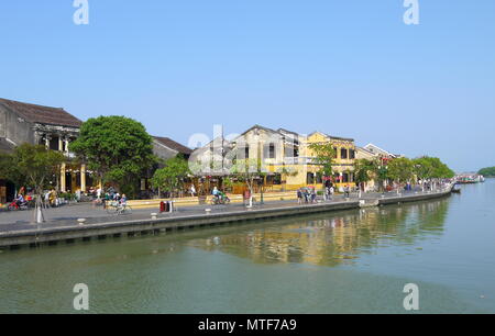 HOI AN, VIETNAM - 19. MÄRZ 2018: Schönen Tag in Hoi An Altstadt mit Blick auf die lokale Bevölkerung, Boote, gelbe Häuser am Ufer des Flusses, und die Touristen Stockfoto