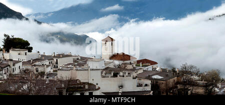 Die alpujarran Dorf Capileira, mit der Katholischen Kirche in Nebel gehüllt, hoch oben in den Bergen der Sierra Nevada in der spanischen Region Andalusien. Stockfoto