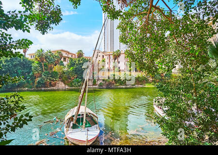 Der Blick auf alte Felucca durch die üppigen Bäume Garten am Fluss, entlang der Corniche Damm o Nil, Kairo, Ägypten. Stockfoto