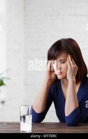 Junge Frau mit starken Kopfschmerzen, die erntehaltefinger zu ihrem Tempel und schließen die Augen vor Schmerz, prepairing Medizin. schwere Migräne.asp Stockfoto