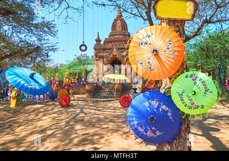 Traditionelle Farbige Sonnenschirme und schöne Puppen sind hängt am Baum neben die alte buddhistische Heiligtum in archäologischen Stätte, Bagan, Myanmar Stockfoto