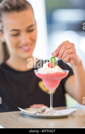 Attraktive junge Frau mit einem schönen Lächeln, während Sie in der Bar Vorbereitung daiquiri trinken. Stockfoto