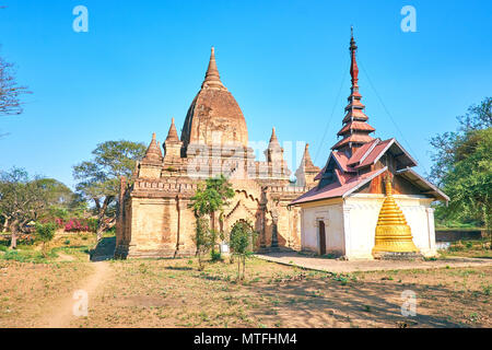 Alte mittelalterliche Tempel Nachbarn mit neueren mit eingebetteten Pagode und Holzdach in alten Bagan Dorf oin Myanmar befinden. Stockfoto