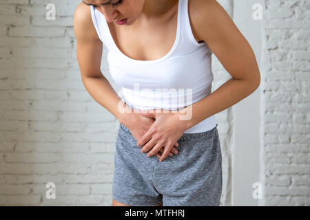 Nahaufnahme von einer jungen Frau, schmerzliche Magenschmerzen, Hände auf ihren Bauch. Körper Schmerzen, Gastritis, Verstopfung, Schmerzen und Krämpfe. Stockfoto