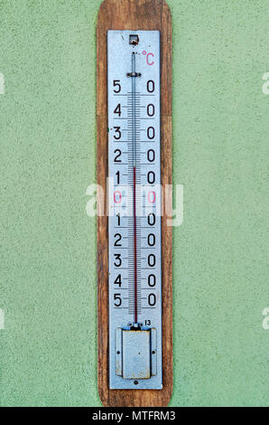 A classic street alcohol thermometer hanging on a plastered wall Stockfoto