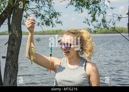 Mädchen, dass ein Fisch in der Hand erwischt, voll Freude und Lächeln Stockfoto