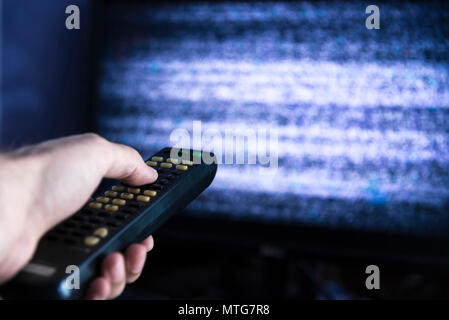 Männliche hand mit Fernbedienung vom TV vor dem Bildschirm Stockfoto