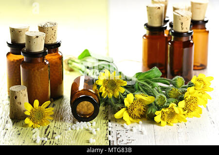 Homöopathische Arnika Pillen in braunen Flaschen auf hölzernen Hintergrund Stockfoto