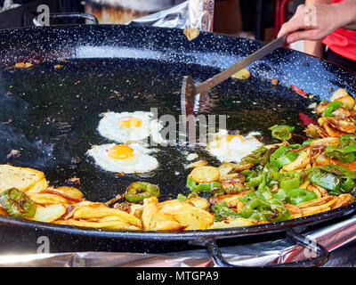 Spanische Eier im Gange. Gebratene Eier mit Kartoffeln und Paprika in der Pfanne. Spanisch Street Food. Stockfoto