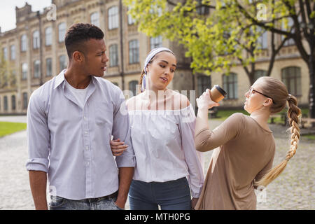 Blonde unaufmerksame Schüler dass Kaffee auf bypasser Stockfoto