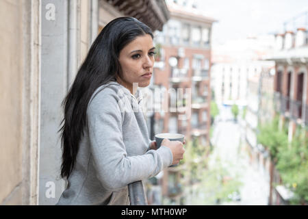 Schönen lateinischen Frau unter Depressionen leiden, eine Tasse Kaffee auf dem Balkon zu Hause. Starrte traurig, Schmerz und Trauer. Krise, drücken Sie Stockfoto