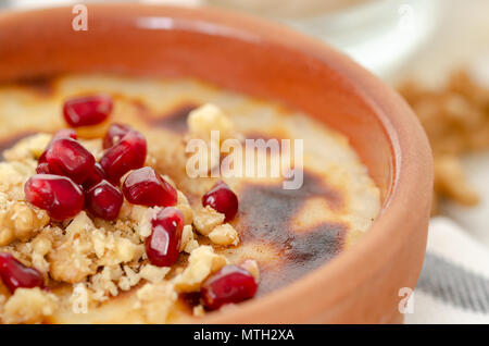 Traditionelle türkische Backofen Milchreis.. Es gibt Walnüsse und Granatapfel auf den Reis puding. Close-up Stockfoto