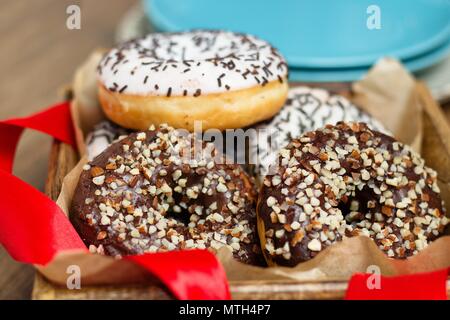 Mehrere Mandeln bestreut Donuts im Holzkasten mit roter Schleife vor Blue Platten Stapel Stockfoto