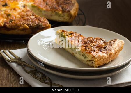 Schneiden von Gemüse pie, oder Quiche, serviert auf einem Teller Stockfoto