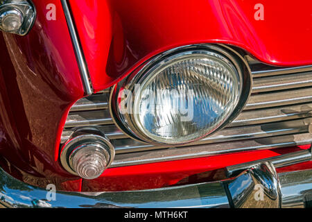 Schließen uo Vintage red Fahrzeug Rechter Frontscheinwerfer Grill, chrom Stoßfänger und rote Motorhaube Stockfoto