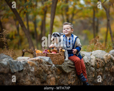 Niedlichen kleinen Jungen mit einem Hund im Herbst. Stockfoto