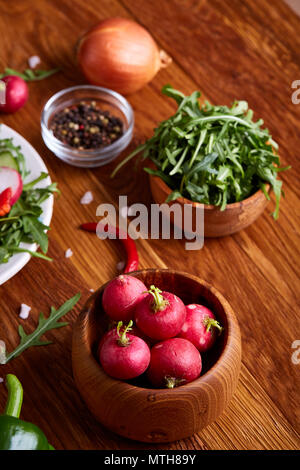 Frische rote Rübe in Houten unter Platten mit Gemüse, Ruccola und Spicies auf rustikalen Holzmöbeln Hintergrund, Nahaufnahme, selektiver Fokus, flacher Dept Stockfoto