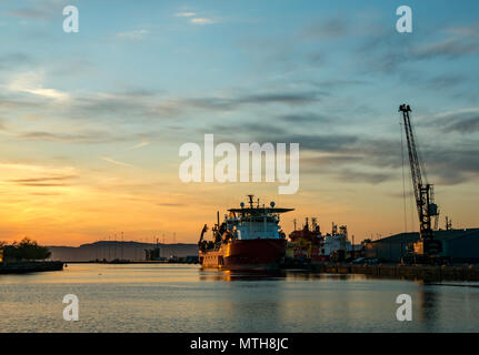 Subsea 7 Schiff, sieben Navica, rohrverlegung Schiff Rockwater und Kran, Eingang Becken, Leith Docks, Edinburgh, Schottland, UK bei Sonnenuntergang mit Orange Sky Stockfoto