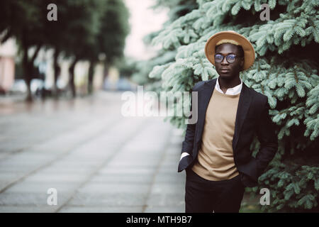 Junge schöne afrikanische amerikanische Geschäftsmann mit Hut zu Fuß auf der Straße Stockfoto