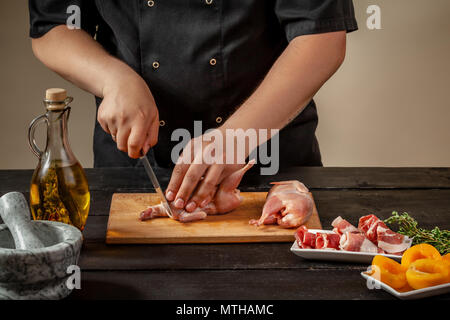 Der Küchenchef bereitet raw Wachtel Schlachtkörper in der Küche. Frisches rohes Fleisch Wachteln bereit für das Kochen auf dem Holzbrett Stockfoto