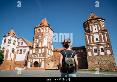 Junge Frau Reisenden mit Rucksack schaut auf mittelalterliche Burg in Mir, Weißrussland Stockfoto