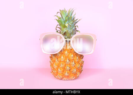 Saftige Ananas in Sonnenbrille auf rosa Hintergrund Stockfoto