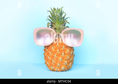 Saftige Ananas in Sonnenbrille auf Türkisfarbenem Hintergrund Stockfoto