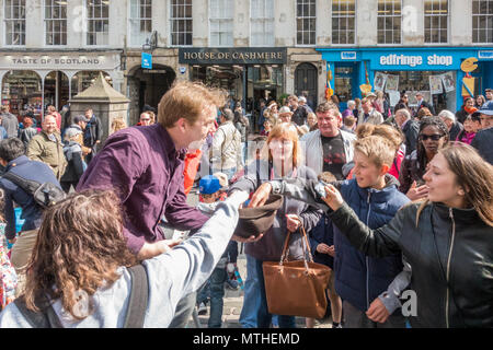 Begeisterte Menge von Personen zahlen Geld geben zu einer Straße Interpret auf der Royal Mile, Edinburgh, Schottland, Großbritannien Stockfoto