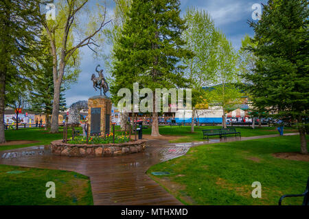 JACKSON HOLE, Wyoming, USA - 23. MAI 2018: Im freien Blick auf touristische Wandern in einem Park in der Nähe der Bronze Statue der Cowboy auf Pferd auf dem Marktplatz in Jackson, Wyoming Stockfoto