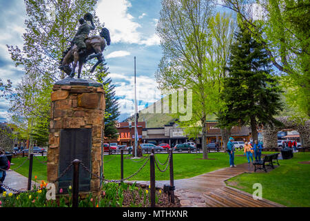 JACKSON HOLE, Wyoming, USA - 23. MAI 2018: Im freien Blick auf touristische Wandern in einem Park in der Nähe der Bronze Statue der Cowboy auf Pferd auf dem Marktplatz in Jackson, Wyoming Stockfoto