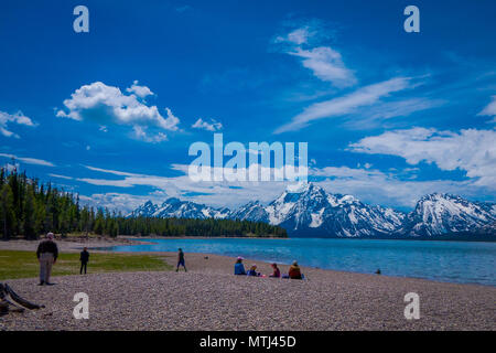 Gruppe von Touristen sitzen auf dem Boden genießen der Landschaft des Grand Teton National Park, Wyoming, Reflexion von Bergen auf der Jackson Lake in der Nähe von Yellowstone Stockfoto