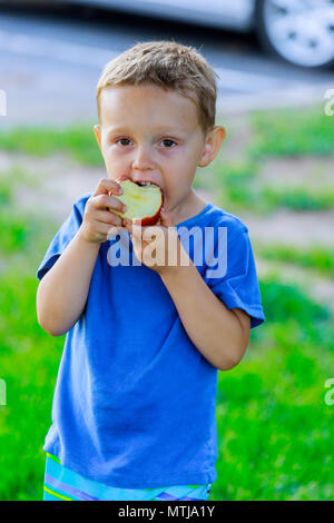 Porträt der jungen mit roten saftigen Apfel in der Hand und grünes Gras im Hintergrund Stockfoto