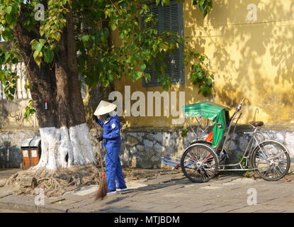 HOI AN, VIETNAM - 20. MÄRZ 2018: Kehrmaschine Arbeiter mit Besen Reinigung der Straße im Zentrum der Weltkulturerbe Stadt Hoi An Stockfoto