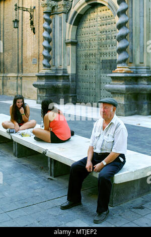 Älterer Mann und zwei Töchtern im Teenageralter eine marmorbank vor eine Tür von Iglesia de San Felipe/San Felipe Kirche, Zaragoza, Aragon, Spanien Stockfoto