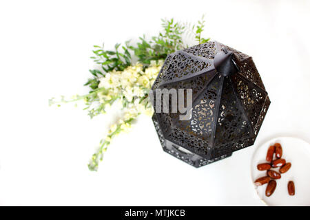 Dekorative dunkel Marokkanische, Arabische Laterne mit Blumen und Platte mit Datum Obst auf dem weißen Tisch. Grußkarte für muslimische heilige Monat Ramadan Kareem, Stockfoto