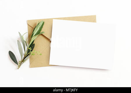 Feminine Schreibwaren, desktop Mock-up-Szene. Leere Grußkarte und Handwerk Umschlag mit Olive Branch, weißem Hintergrund. Flach, Ansicht von oben. Stockfoto