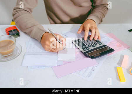 Hand Finanzen tun und auf dem Schreibtisch über Kosten zu Hause Büro berechnen. Stockfoto