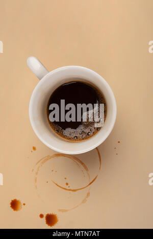 Tasse Espresso mit kaffeeflecken auf beige Tabelle von oben. Überstunden. Stockfoto