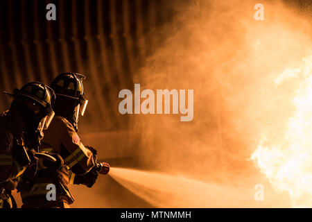 Feuerwehrmänner vom 23 d Bauingenieur Squadron eine Flamme während der Nacht, Live Fire Training löschen, Jan. 10, 2017, bei Moody Air Force Base, Ga. Diese Schulung ist eine jährliche Anforderung für Moody Feuerwehrmänner und ist nur eine der Möglichkeiten, die Sie bereit bleiben Menschen, Eigentum und Umwelt vor Brände und Katastrophen zu schützen. (U.S. Air Force Foto: Staff Sgt. Ryan Callaghan) Stockfoto