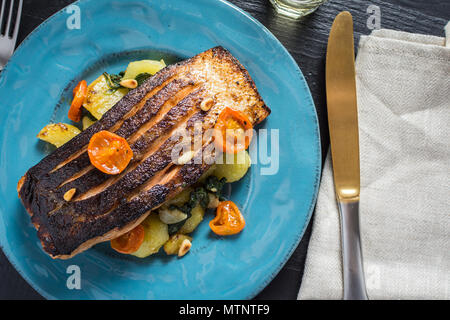 Knusprige Haut gegrillter Lachs mit Gemüse auf blauen Platte Stockfoto