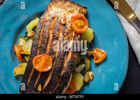 Knusprige Haut gegrillter Lachs mit Gemüse auf blauen Platte Stockfoto