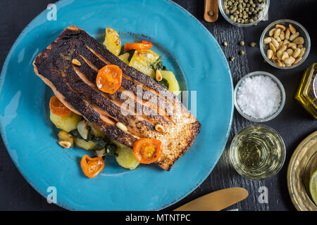 Knusprige Haut gegrillter Lachs mit Gemüse auf blauen Platte Stockfoto