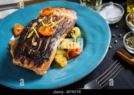 Knusprige Haut gegrillter Lachs mit Gemüse auf blauen Platte Stockfoto