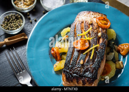 Knusprige Haut gegrillter Lachs mit Gemüse auf blauen Platte Stockfoto