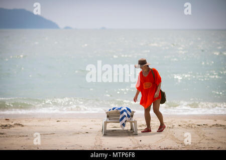 Eine blonde Frau Spaziergänge am Strand entlang am Damai Laut Resort in Malaysia. Stockfoto